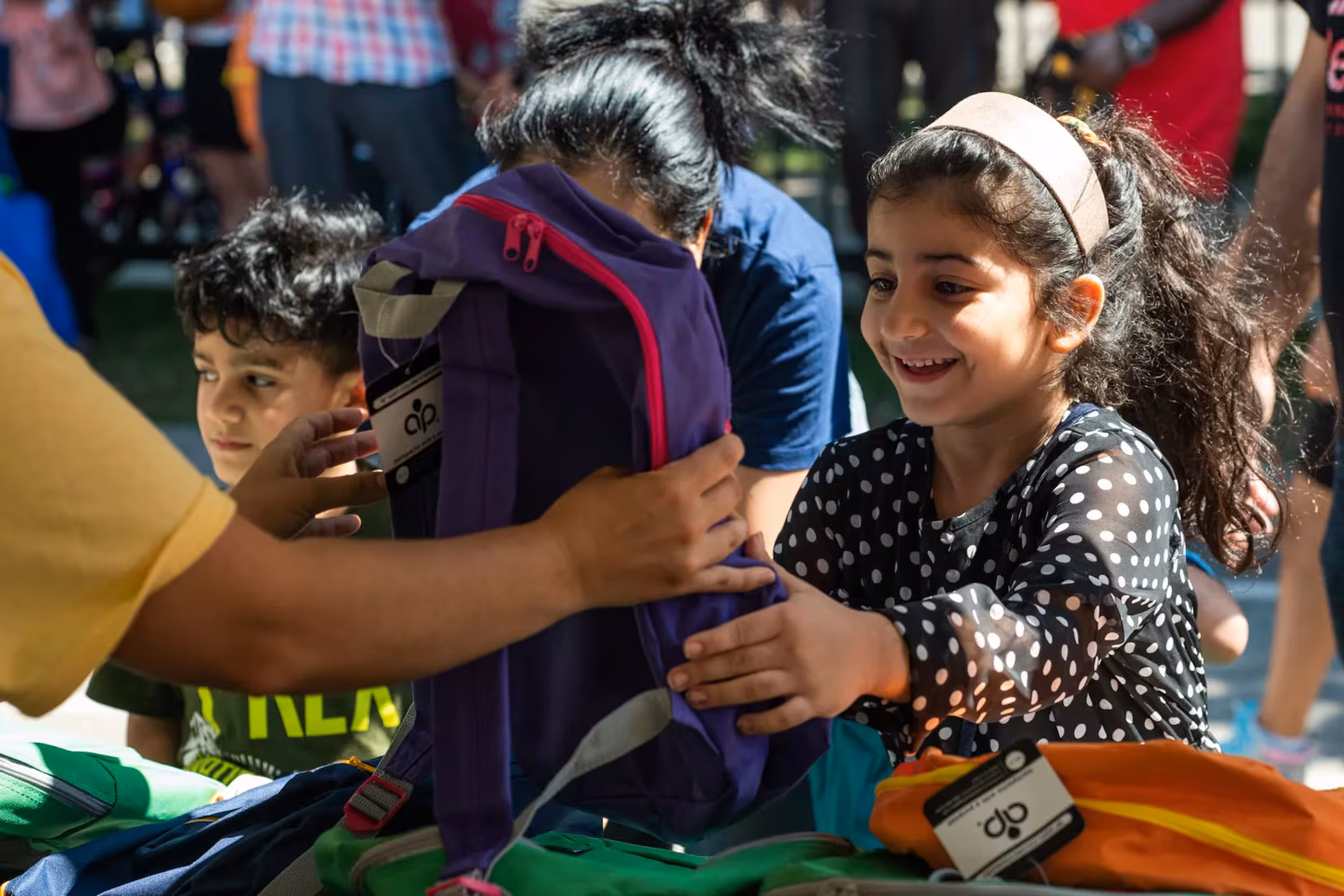 A little girl smiling while choosing a new backpack