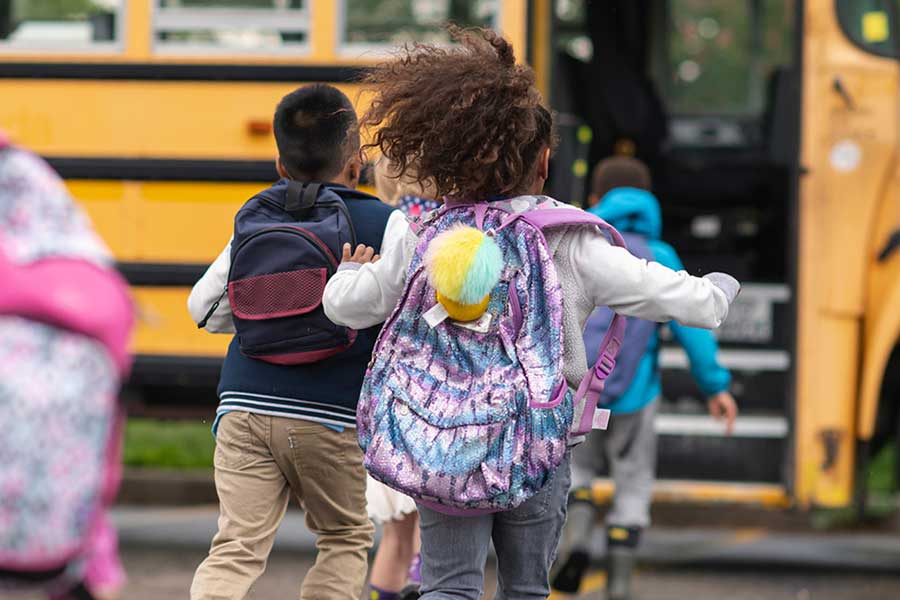 Kids running to the school bus with their backpacks