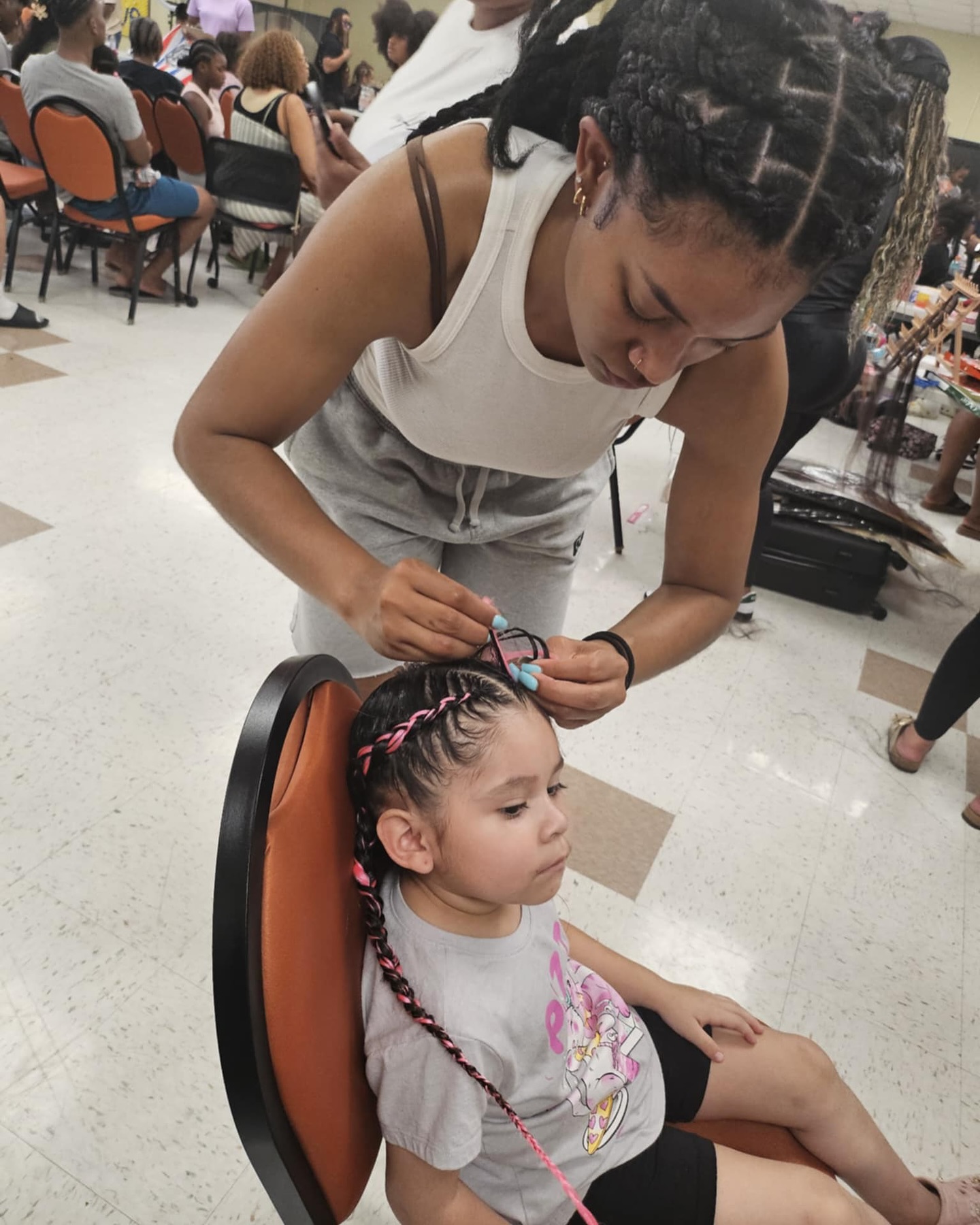 Stylist braiding a young girl's hair at the event